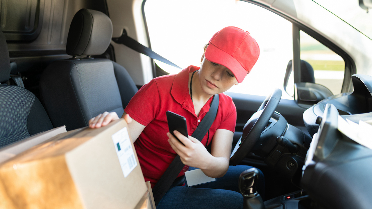 Deliver driver in the truck scanning a barcode on a parcel with a smartphone
